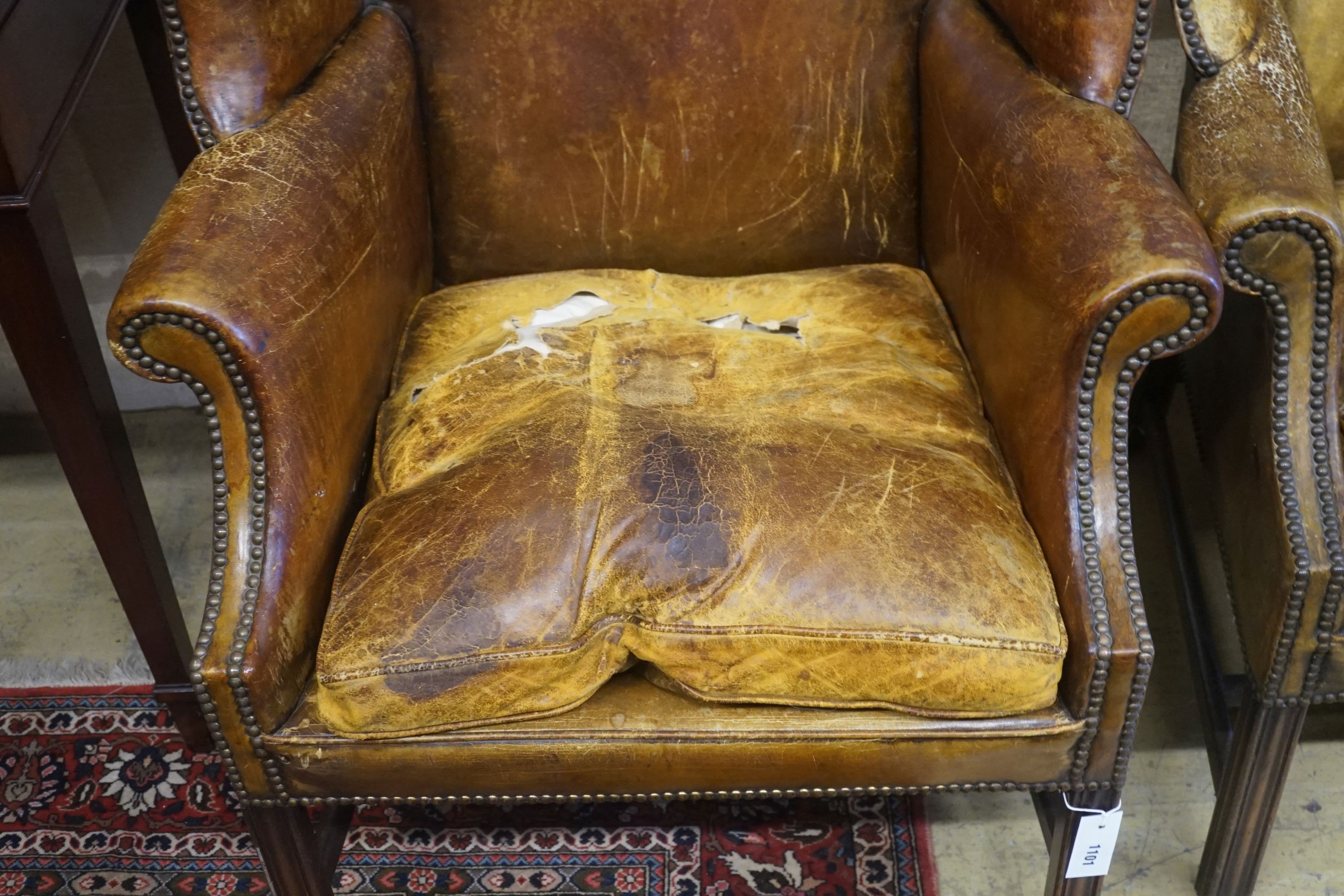 A pair of George III style tanned leather wing armchairs